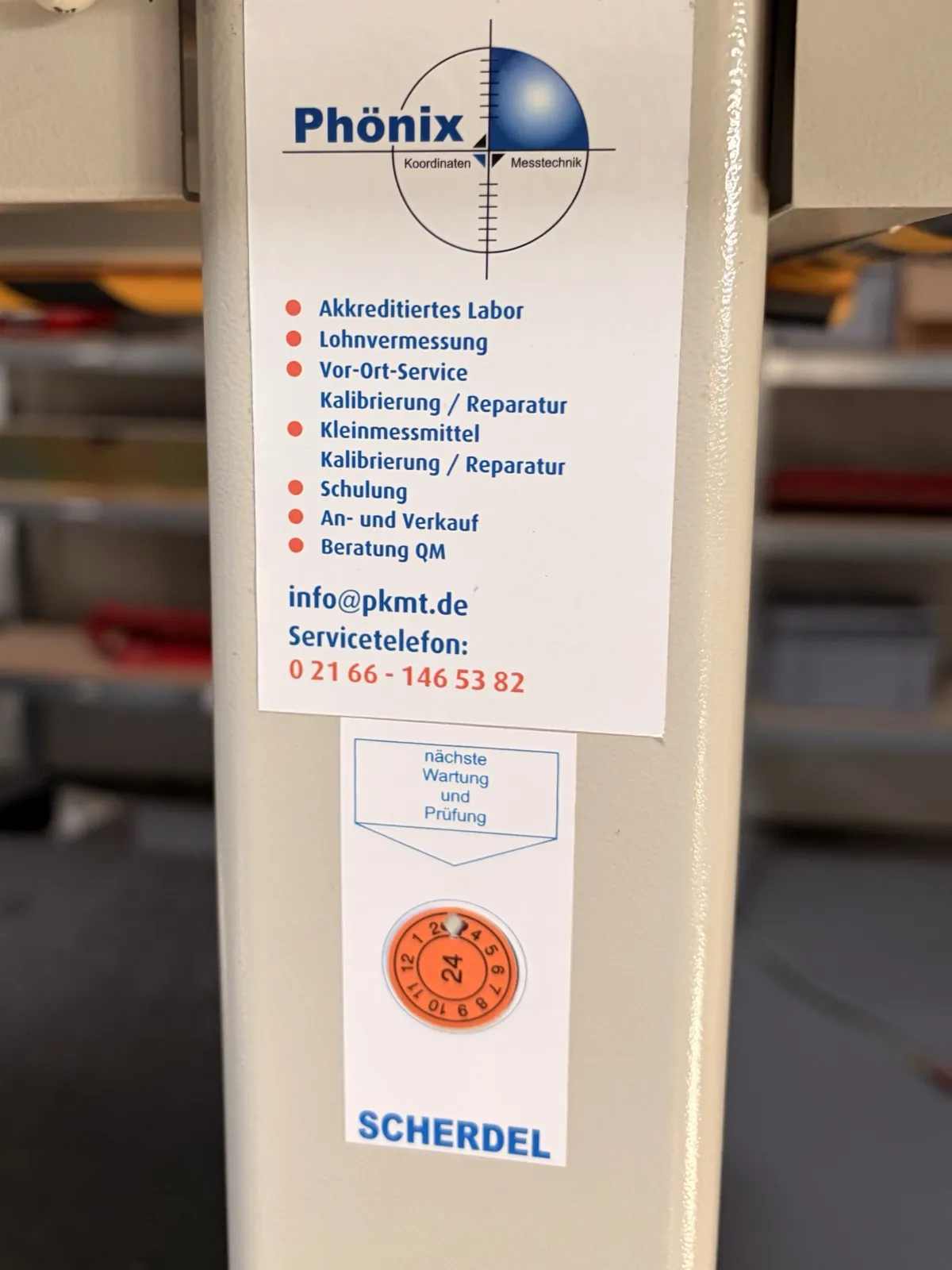 Phönix-Serviceaufkleber und Prüfplakette mit nächstem Wartungstermin an einer Messmaschine